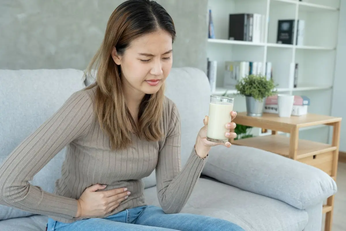 Intolerancia Alimentar moca segurando um copo com leite com dor abdominal
